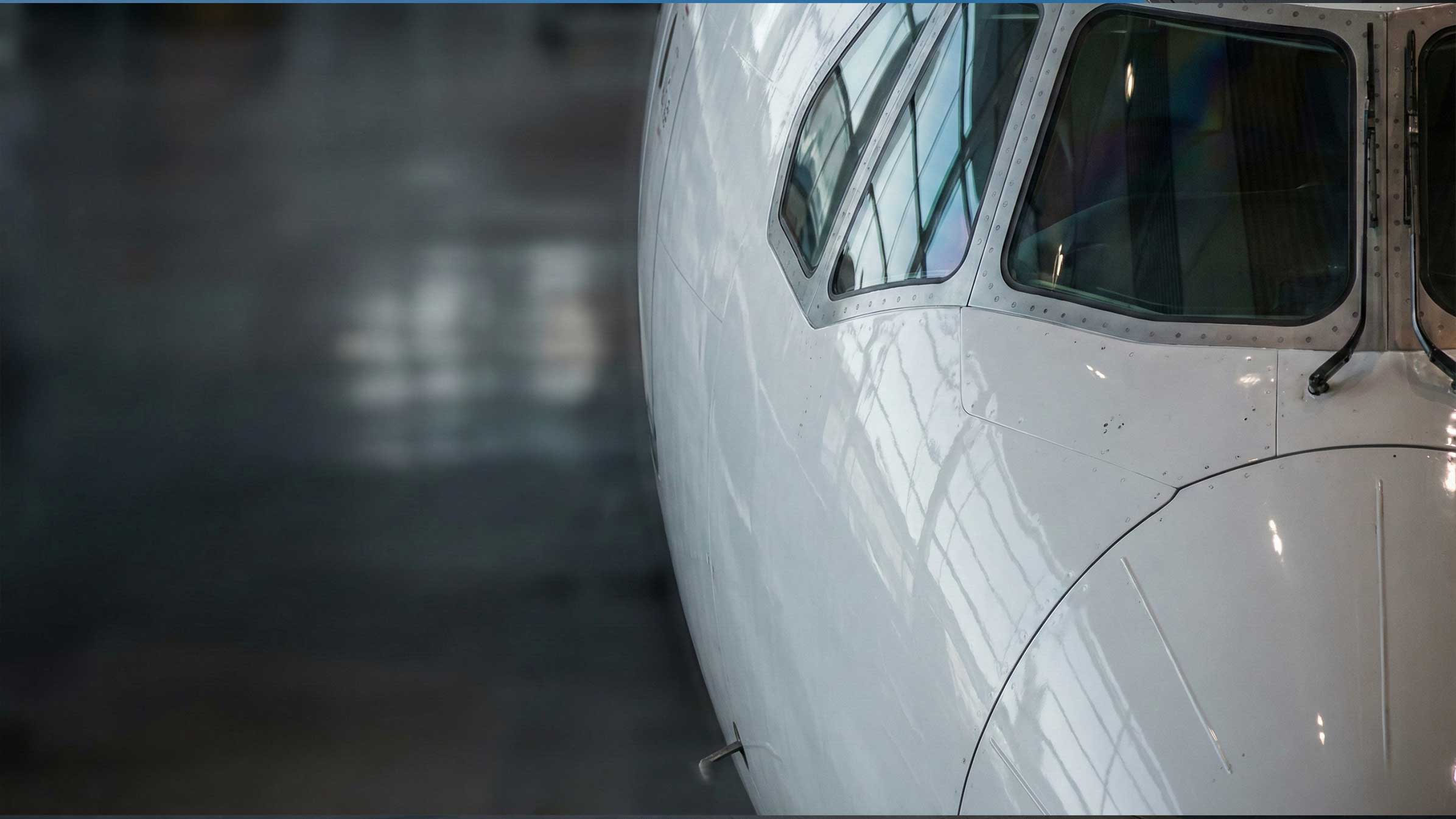 Business aircraft nose and cockpit windows on an airport ramp.
